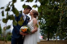 a bride and groom are standing under the trees