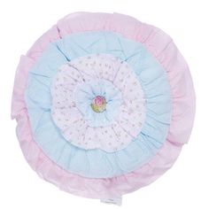 a pink and blue decorative pillow with ruffles on the bottom, sitting on a white surface