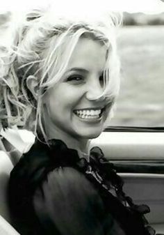 a woman sitting in the back seat of a car with her hair blowing in the wind