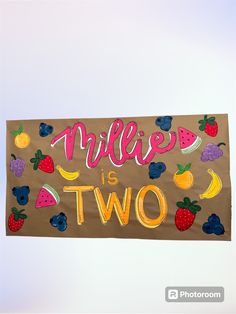 a sign that says millies is two with fruits and berries painted on the side