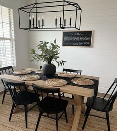 a dining room table with black chairs and plates on it