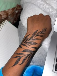 a person with a tattoo on their arm holding a laptop