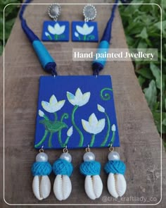 the necklace and earring are made from fabric with white flowers on blue, green leaves