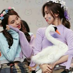 two girls are standing next to each other and one is holding a swan