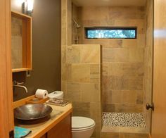 a bathroom with a sink, toilet and shower stall in the background is a wooden cabinet