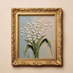 a painting with white flowers in a gold frame on the wall next to a beige wall