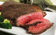 a large piece of steak and broccoli on a white plate with a fork