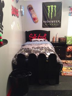 a bedroom with a bed and skateboard on the wall next to two black trash cans