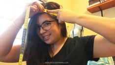 a woman is measuring her long hair with a tape around her head and wearing glasses