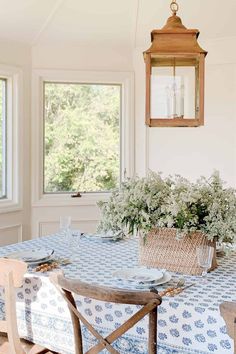 a dining room table with blue and white patterned cloth on it, surrounded by wooden chairs