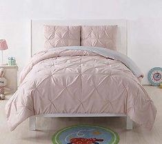 a bed with pink comforter and pillows in a room next to a teddy bear