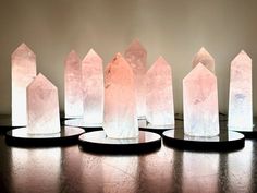 five crystal obelisk standing on black bases in front of a white wall