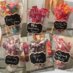 there are many candies in the glass vases with chalkboard signs on them