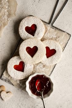 heart shaped cookies on a plate with jam in the middle and two hearts cut out to look like they are sitting next to each other