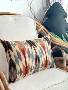 a white chair with a pillow on top of it next to a basket and plant