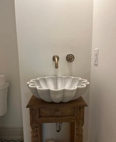 a white bowl sink sitting on top of a wooden stand next to a toilet in a bathroom