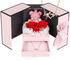 a pink teddy bear in a box with roses