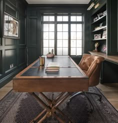 a leather chair sits in front of a desk with a book on it and bookshelves behind it