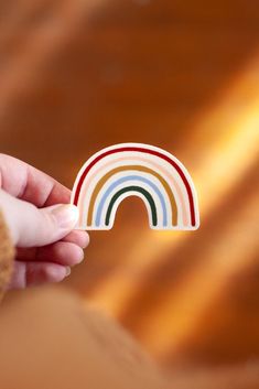 a person holding a rainbow shaped sticker in their hand