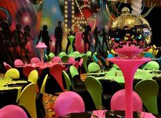 a room filled with lots of tables covered in colorful chairs and disco ball centerpieces