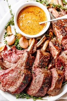 steaks and garlic on a plate with dipping sauce