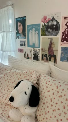 a stuffed dog laying on top of a bed in a room with pictures on the wall