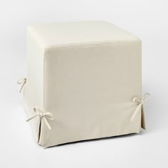 a white square ottoman with ties around the edges