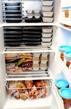 an open refrigerator filled with lots of food and plastic containers on the shelves in front of it