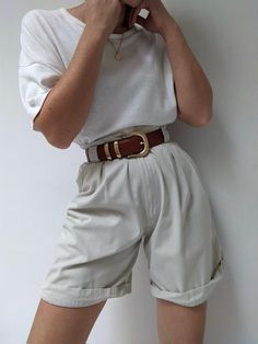 Classic pleated shorts in a khaki cotton. Shorts have a high-rise fit with v-cut at the front of the waist. Includes belt loops, pockets and a cuffed design to the leg. Tag reads Ashworth There are a few small discolored spots at the front waistline - does not affect the overall look or wear. Spring Shorts With Belt Detail, Spring High Waist Shorts With Belt Detail, Casual High Waist Shorts With Belt Detail, Casual High-waist Shorts With Belt Detail, Summer Cotton Bottoms With Belt, Chic Cotton Bermuda Shorts With Belt Loops, Chic Belted Shorts For Summer, Chic Summer Shorts With Belt Detail, Classic High-waisted Shorts With Belt Loops