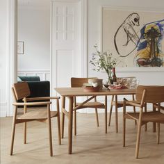 a dining room table and chairs with artwork on the wall