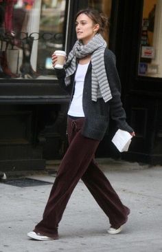 a woman walking down the street with a cup of coffee in her hand and a scarf around her neck