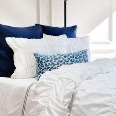 a bed with blue and white pillows on top of it next to a black lamp