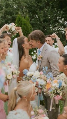 a group of people standing around each other with flowers in their hair and one man kissing the woman's forehead