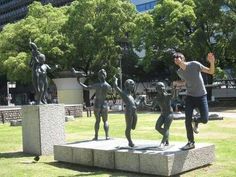 a man standing next to some statues in a park