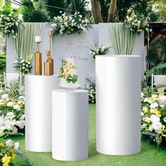 three large white vases sitting on top of a grass covered field next to flowers