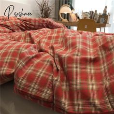 a red and green plaid comforter sitting on top of a bed