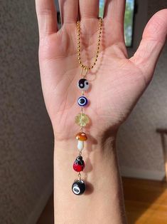 a person's hand is holding several different beads on the wrist, and one has a gold chain with an evil eye charm hanging from it