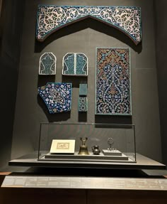 an elaborately designed display case with blue and white tiles on the wall above it