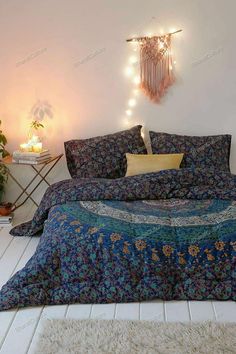 a bed with blue and green bedspread in a bedroom next to a plant