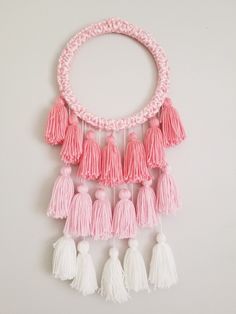 a pink and white tasselled necklace on a white surface with other tasselled beads