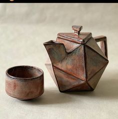 a teapot and cup sitting on top of a table next to an empty bowl