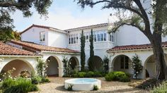 a large white house with a pool in the front yard and lots of trees around it