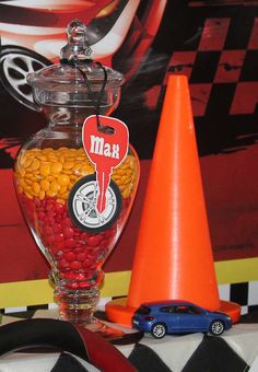 a candy jar filled with red and yellow candies next to an orange traffic cone