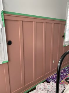 a room with pink paneling on the walls and green trim around the window sill