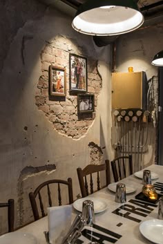 a dining room table with plates and utensils on it in front of a brick wall