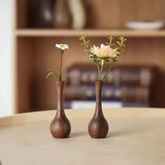 two wooden vases with flowers in them on a table