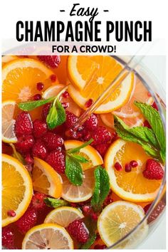 a glass bowl filled with oranges, raspberries and mint leaves next to the words easy champagne punch for a crowd