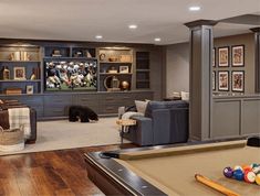 a game room with pool table, couches and entertainment center in the back ground