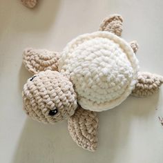 a crocheted turtle laying on the ground with it's head up and eyes closed