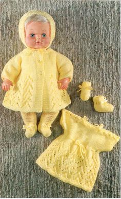 a baby doll wearing a yellow knitted outfit and matching booties is laying on the floor